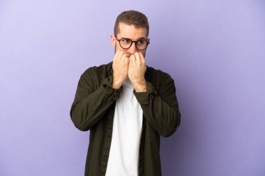 Mor arka planda izole edilmiş yakışıklı beyaz bir adam gergin ve korkmuş bir şekilde elleriyle suni teneffüs yapıyor.