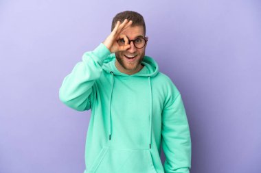 Mor arka planda izole edilmiş yakışıklı beyaz adam parmaklarıyla 