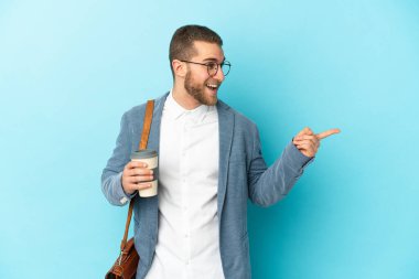 Kafkasyalı genç işadamı mavi arka planda izole edilmiş bir şekilde parmak ucunda bir ürün sunuyor.