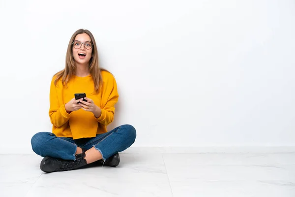 Giovane Donna Caucasica Seduta Sul Pavimento Isolata Sfondo Bianco Sorpreso — Foto Stock