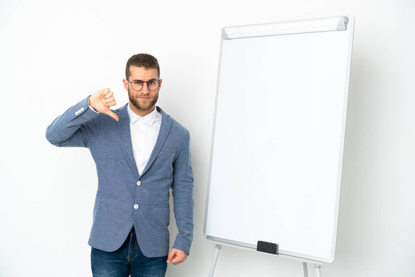 Young business woman giving a presentation on white board isolated on white background showing thumb down with negative expression