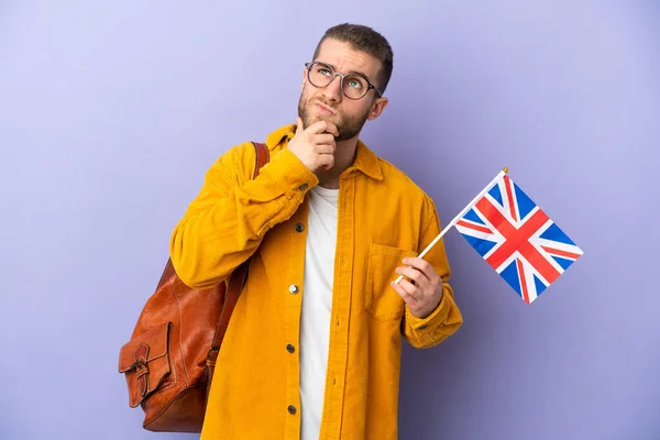 拿着英国国旗的年轻高加索人 背景紫色 令人怀疑 — 图库照片