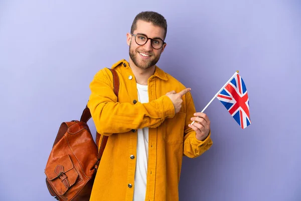 Mladý Běloch Drží Vlajku Spojeného Království Izolovanou Fialovém Pozadí Ukazující — Stock fotografie