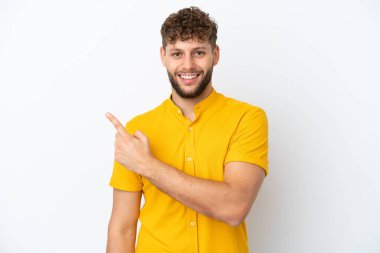 Beyaz arka planda izole edilmiş yakışıklı beyaz adam şaşırmış ve işaret ediyor.