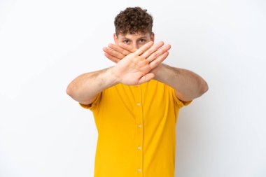 Beyaz arka planda izole edilmiş yakışıklı beyaz bir adam bir hareketi durdurmak için eliyle jest yapıyor.