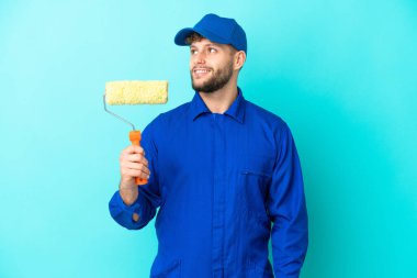 Kafkasyalı ressam mavi arka planda izole edilmiş bir şekilde yukarı bakarken bir fikir düşünüyor.