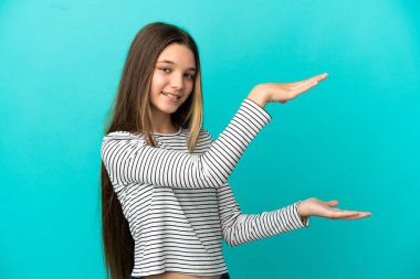 İzole edilmiş mavi arkaplan üzerinde küçük bir kız bir reklam eklemek için kopyalama alanı tutuyor