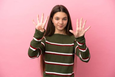 Küçük bir kız pembe arka planda dokuz parmağıyla sayıyor.