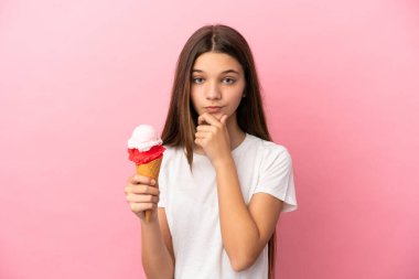 Kornet dondurması ile izole edilmiş pembe arka planı olan küçük bir kız.