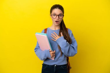 İzole edilmiş sarı arka planı olan öğrenci bir kadın sağa bakarken şaşırmış ve şok olmuştu.