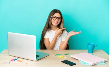 Masada dizüstü bilgisayarı olan küçük bir kız. Mavi arka plan üzerinde. Kopyalama alanı hayali bir şey tutuyor.