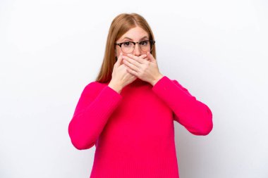 Beyaz arka planda izole edilmiş genç, kızıl saçlı bir kadın elleriyle ağzını kapatıyor.