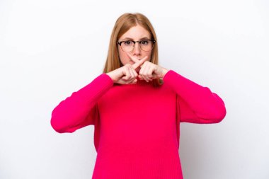 Beyaz arka planda izole edilmiş genç kızıl saçlı kadın sessizlik işareti gösteriyor.