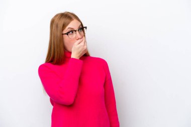 Beyaz arka planda izole edilmiş genç kızıl saçlı kadın yan tarafa bakarken sürpriz jest yapıyor.