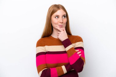 Genç kızıl saçlı kadın, beyaz arka planda izole edilmiş bir şekilde bakarken bir fikir düşünüyor.