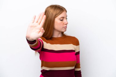 Beyaz arka planda izole edilmiş genç kızıl saçlı kadın dur hareketi yapıyor ve hayal kırıklığına uğruyor.