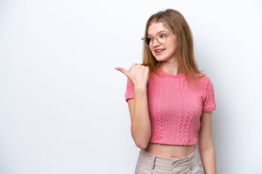Beyaz arka planda izole edilmiş genç Rus kız bir ürünü sunmak için kenarı işaret ediyor.
