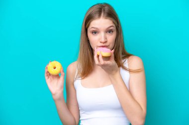 Genç Rus kız elinde donutla mavi arka planda izole edilmiş.