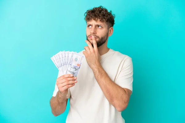 Jonge Kaukasische Man Neemt Veel Geld Geïsoleerd Blauwe Achtergrond Met — Stockfoto