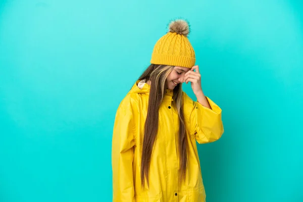 穿着防雨外套的小女孩在孤零零的蓝底笑着 — 图库照片