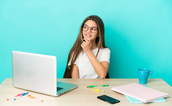 Menina Uma Mesa Com Laptop Sobre Fundo Azul Isolado Olhando — Fotografia de Stock