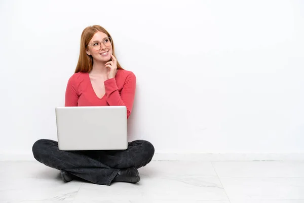 Молодая Рыжая Женщина Ноутбуком Сидящая Полу Изолированы Белом Фоне Думая — стоковое фото