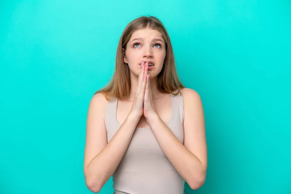 stock image Teenager Russian girl isolated on blue background keeps palm together. Person asks for something