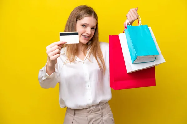 十代のロシア人の女の子孤立した上の黄色の背景保持ショッピングバッグとクレジットカード — ストック写真