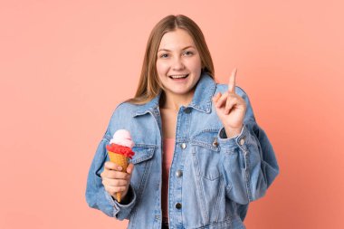 Pembe arka planda izole edilmiş kornet dondurması olan Ukraynalı genç kız harika bir fikre işaret ediyor.