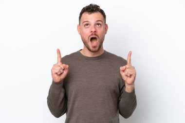 Beyaz arka planda izole edilmiş genç Brezilyalı adam şaşırmış ve yukarı bakıyor.