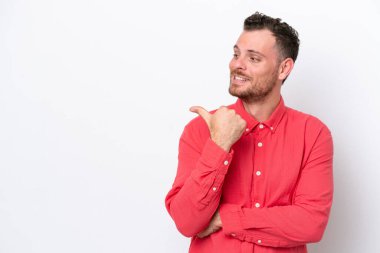 Beyaz arka planda izole edilmiş genç Brezilyalı bir adam bir ürün sunmak için kenarı işaret ediyor