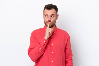 Beyaz arka planda izole edilmiş genç Brezilyalı bir adam sessizlik işareti gösteriyor. Parmağını ağzına sokuyor.