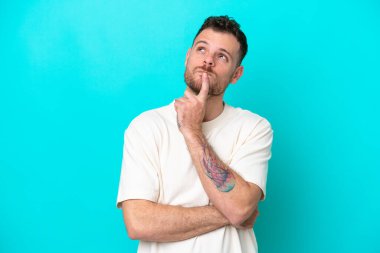 Genç Brezilyalı bir adam mavi arka planda izole edilmiş.