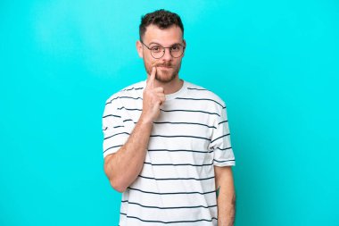 Genç Brezilyalı bir adam mavi arka planda soyutlanmış ve düşünüyor