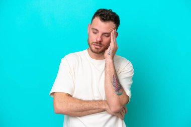 Mavi arka planda baş ağrısı olan genç Brezilyalı bir adam izole edilmiş.