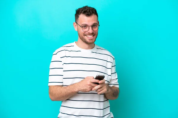 Genç Brezilyalı Adam Mavi Arka Planda Izole Edilmiş Cep Telefonuyla — Stok fotoğraf