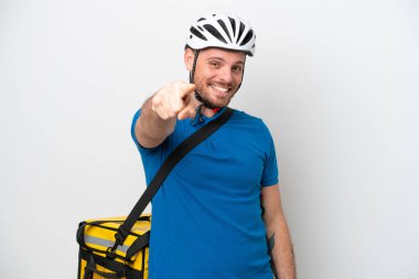 Beyaz arka planda izole edilmiş termal sırt çantalı genç Brezilyalı adam kendine güvenen bir ifadeyle sana parmak basıyor.