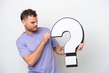 Beyaz arka planda izole edilmiş genç Brezilyalı bir adam soru işareti simgesi taşıyor