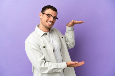 İzole edilmiş mor arkaplan üzerinde Brezilyalı bir adam bir reklam eklemek için kopyalama alanı tutuyor