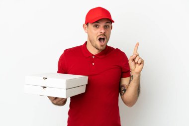 Pizza teslimatçısı üniformalı adam izole edilmiş beyaz duvardan pizza kutuları alıyor. Çözümü bulmak için parmağını kaldırıyor.