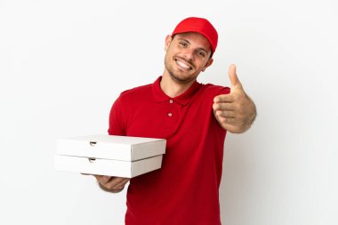 Pizza teslimatçısı üniformalı adam izole edilmiş beyaz duvarın üzerinden pizza kutuları alıyor ve iyi bir anlaşma için el sıkışıyor.