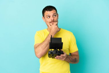 Brezilyalı bir adam uzaktan kumandayla izole edilmiş mavi arkaplanı kontrol ediyor.