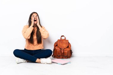 Genç Brezilyalı bir kız yerde oturmuş bağırıyor ve bir şeyler söylüyor.