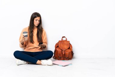 Brezilya 'lı genç bir bayan kahve almak için yerde oturuyor ve bir de cep telefonu var.