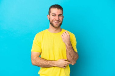 Mavi arka planda izole edilmiş yakışıklı beyaz adam gülüyor.