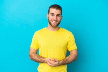 Mavi arka planda izole edilmiş yakışıklı beyaz adam gülüyor.