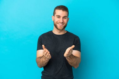 Mavi arka planda izole edilmiş yakışıklı beyaz adam bir konferansın sunumundan sonra alkışlıyor.