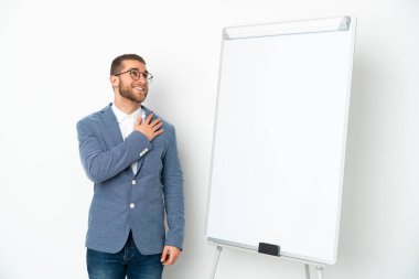 Beyaz arka planda izole edilmiş beyaz panoda sunum yapan genç iş kadını gülümserken yukarı bakıyor.