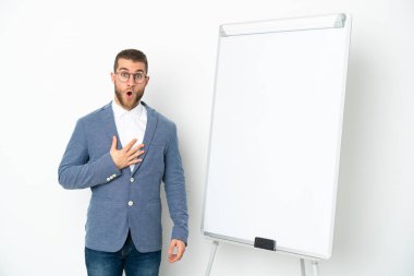 Beyaz arka planda izole edilmiş beyaz panoda sunum yapan genç bir iş kadını sağa bakarken şaşırmış ve şok olmuştu.