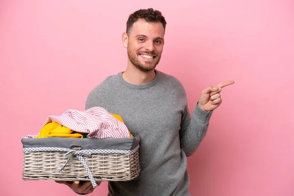 Ung Brasiliansk Man Som Håller Klädkorg Isolerad Rosa Bakgrund Pekar — Stockfoto